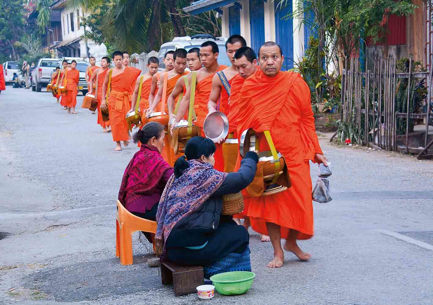 Mönche erhalten Essensspenden von Gläubigen.